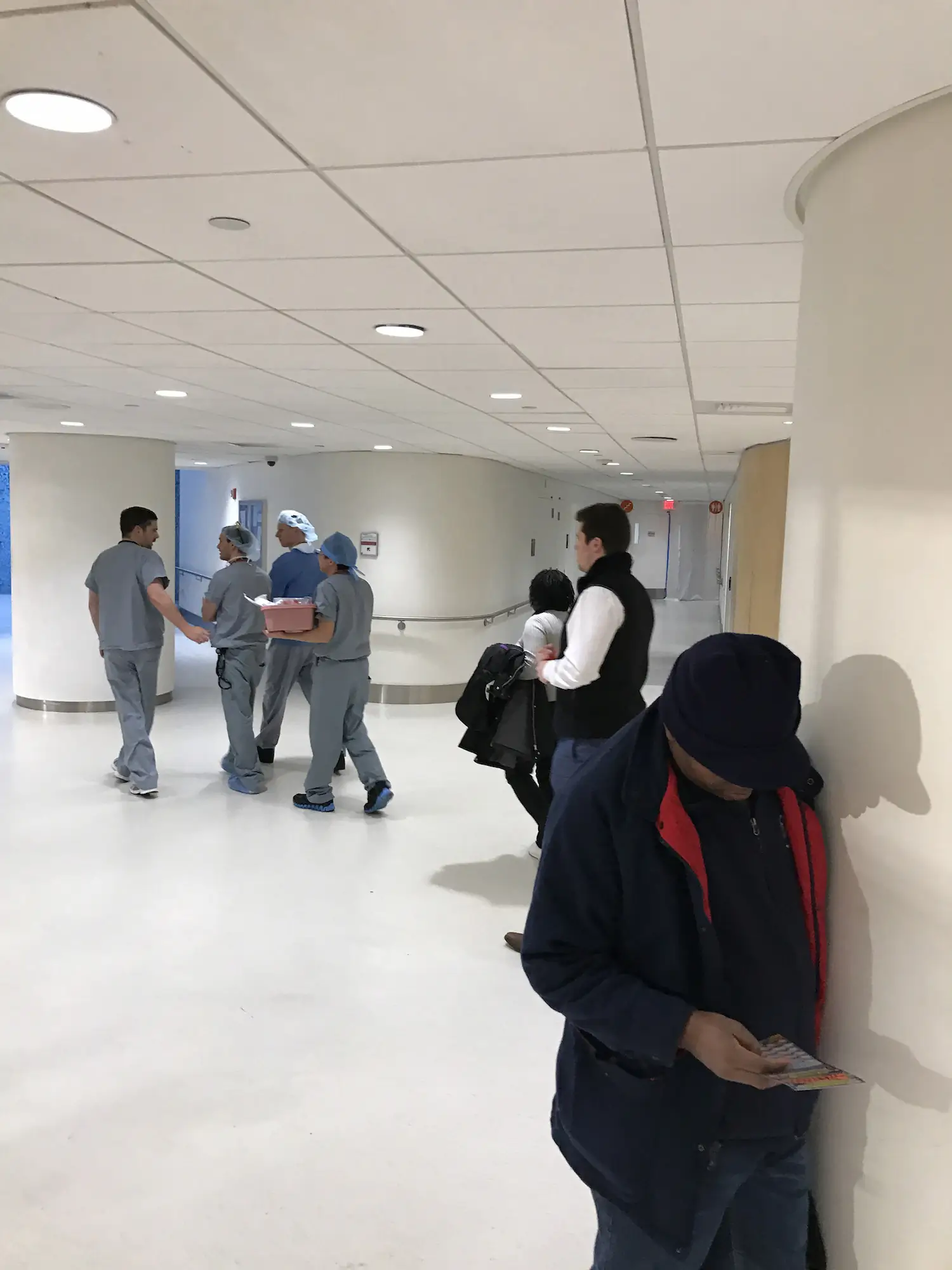 Trabajadores y personal médico reunidos en el pasillo de una oficina moderna