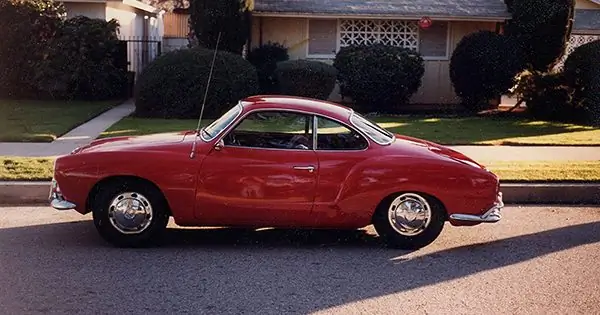 Karmann Ghia coupé rojo brillante de 1967 estacionado en una calle residencial