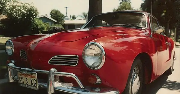 Volkswagen Karmann Ghia rojo brillante de 1967 estacionado en una calle residencial soleada